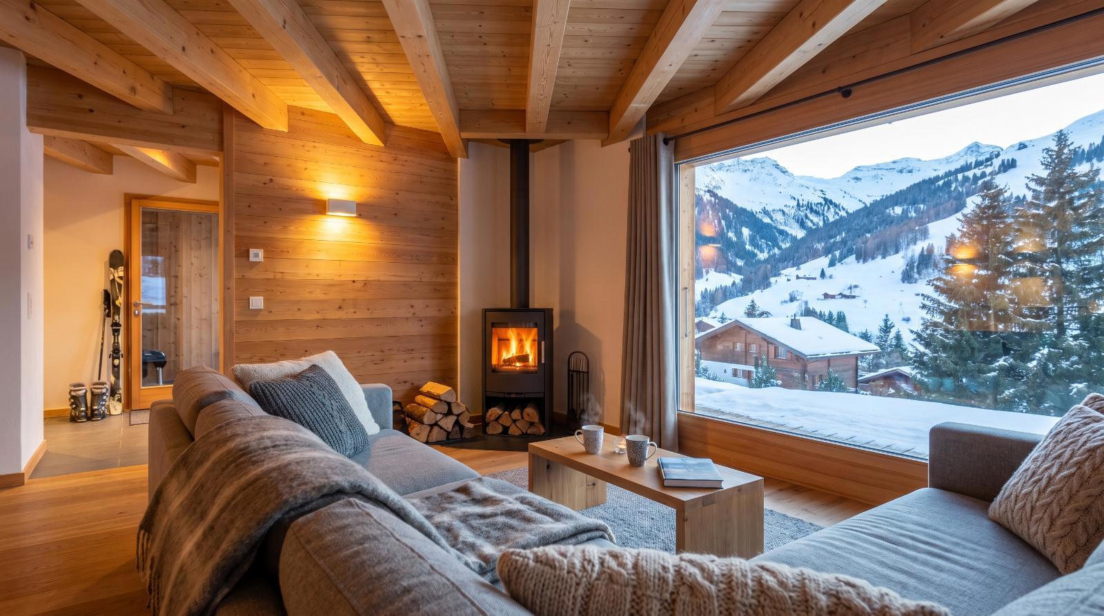Living room of a holiday apartment in Verbier with a wood stove and views of the snowy slopes